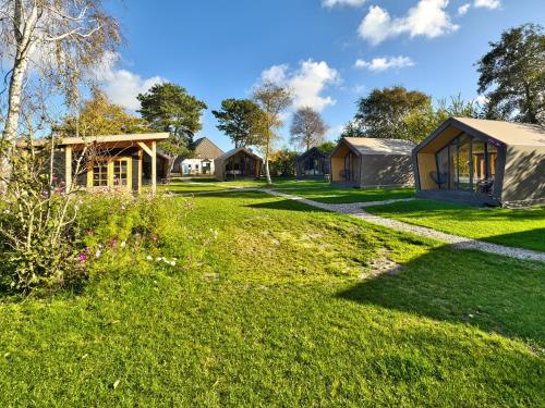 une cour herbeuse avec des maisons en arrière-plan dans l'établissement Tenthuisje in het groen, een suite met eigen badkamer, à Callantsoog