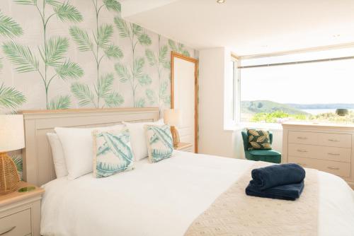 a bedroom with a large white bed with blue pillows at Lower Upover in Woolacombe