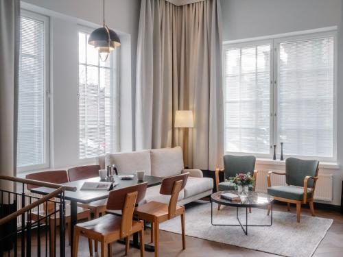 een woonkamer met een bank en een tafel en stoelen bij Bob W Koti Katajanokka in Helsinki