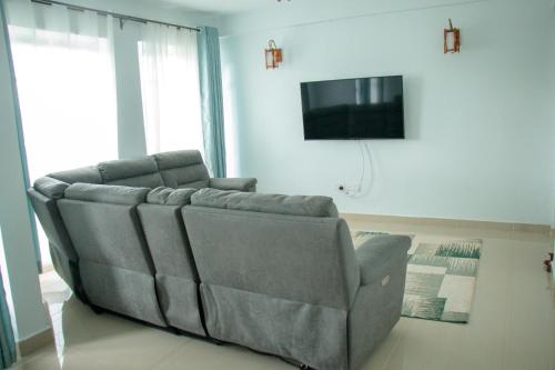 a couch sitting in a living room with a television at Zoe Homes 1br and 2br Apartment Greypoint 406 in Kericho