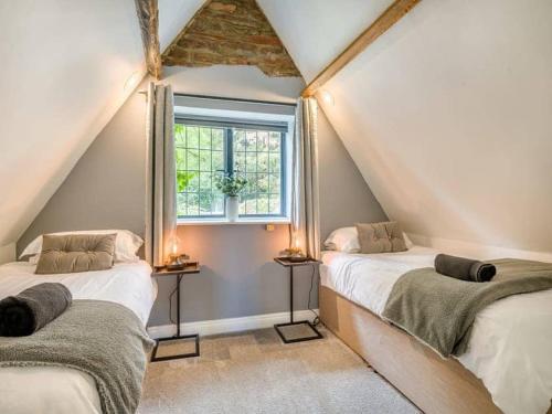 two beds in a attic room with a window at luxury 2 bed cosy cottage with hot tub and childrens play area hambrook Bristol in Bristol