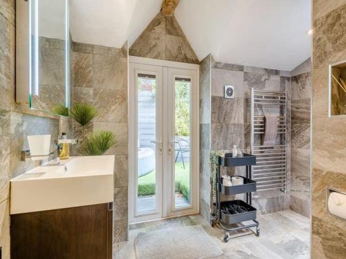 a bathroom with a sink and a shower with a window at luxury 2 bed cosy cottage with hot tub and childrens play area hambrook Bristol in Bristol