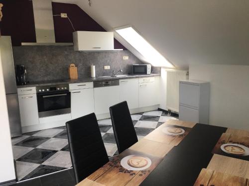 a kitchen with a dining table and a kitchen with white cabinets at Ferienwohnung Ludwig in Karlstadt