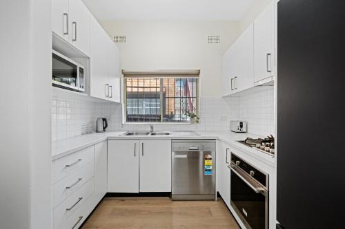 a kitchen with white cabinets and a stainless steel dishwasher at Burwood New 2 Bedroom 2 Bath Apt Free Parking in Sydney
