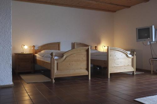 a bedroom with two wooden beds and a tv at Pension Steiger in Bad Griesbach