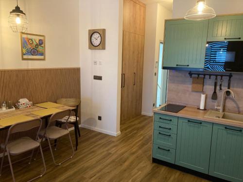 cocina con armarios verdes, mesa y reloj en Štýlový apartmán A409 v centre NR, parkovanie v cene, en Nitra