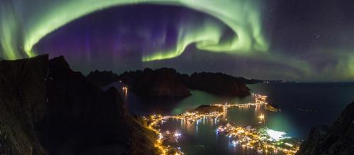 an aurora over a city at night with lights at Moskenes Cabin in Moskenes