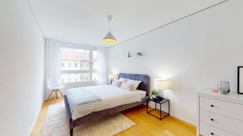 a white bedroom with a bed and a window at Sublime contemporary apartment in the city centre in La Chaux-de-Fonds
