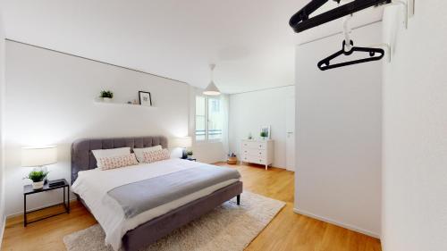 a bedroom with a bed and a white wall at Sublime contemporary apartment in the city centre in La Chaux-de-Fonds