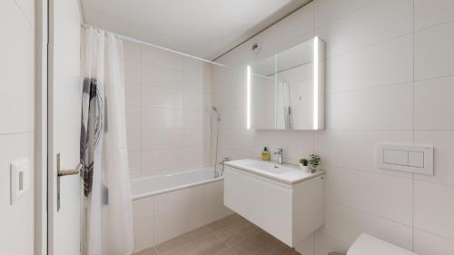 La salle de bains blanche est pourvue d'un lavabo et d'un miroir. dans l'établissement Sublime contemporary apartment in the city centre, à La Chaux-de-Fonds