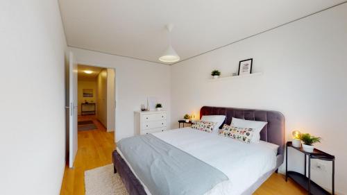 a bedroom with a large bed with white walls at Sublime contemporary apartment in the city centre in La Chaux-de-Fonds