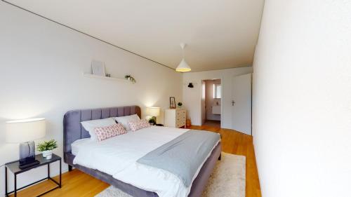 a bedroom with a large bed with white sheets and pink pillows at Sublime contemporary apartment in the city centre in La Chaux-de-Fonds