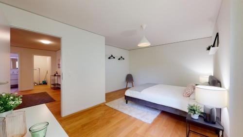 a white bedroom with a bed and a living room at Sublime contemporary apartment in the city centre in La Chaux-de-Fonds