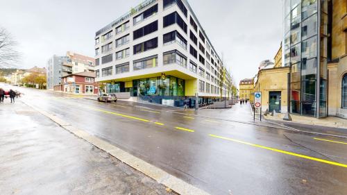 an empty city street with buildings on a rainy day at Sublime contemporary apartment in the city centre in La Chaux-de-Fonds