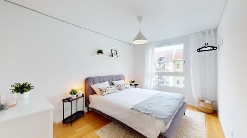 a white bedroom with a bed and a window at Sublime contemporary apartment in the city centre in La Chaux-de-Fonds