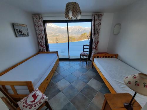 a room with two beds and a window with a view at T2 Balcon de l'Embrunais in Saint-Sauveur