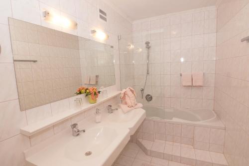 a white bathroom with a tub and a sink at Schiederhof in Mittersill