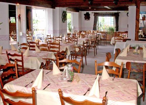 uma sala de jantar com mesas brancas e cadeiras de madeira em Hotel-Restaurant Zum Dorfkrug em Winterberg