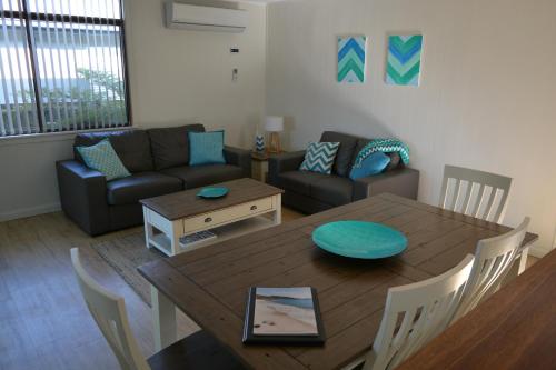 a living room with a table and a couch at Baltica Beach House in Culburra Beach