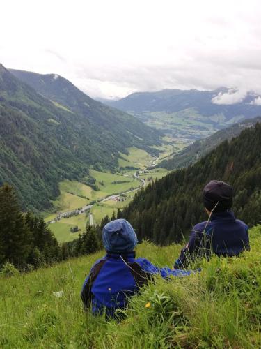 two people sitting on a hill looking at a valley at Schiederhof in Mittersill