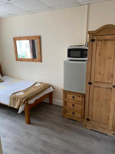 ein Schlafzimmer mit einem Bett und einer Mikrowelle auf einem Schrank in der Unterkunft Clarendon Lodge - accommodation only in Skegness