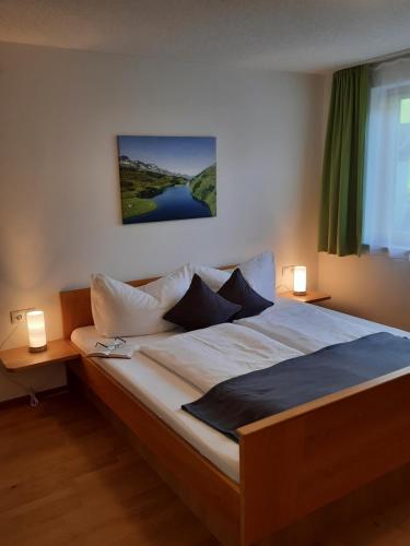 1 dormitorio con 1 cama grande y 2 lámparas en Ferienwohnung Schrofamühli, en Silbertal