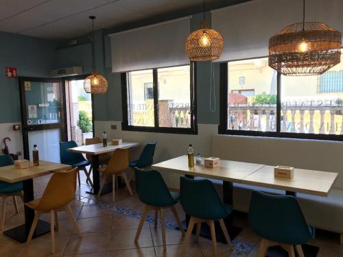 a dining room with tables and chairs and windows at Hotel Macavi Playa in Rota