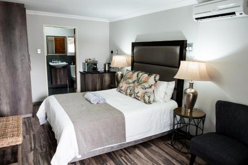 a hotel room with a bed and a chair at Villa Gracia Guesthouse in Klerksdorp