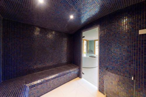 a bathroom with a blue tiled wall with a bench at Chalet L'Urson, spacieux, jacuzzi, hammam et sauna in Gérardmer