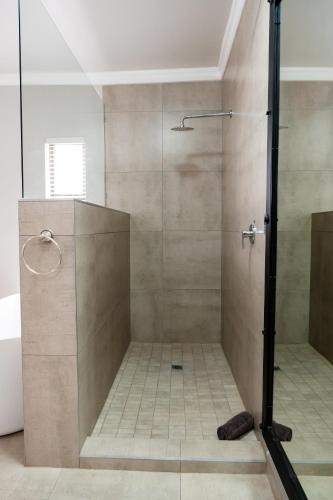 a shower with a glass door in a bathroom at Villa Gracia Guesthouse in Klerksdorp