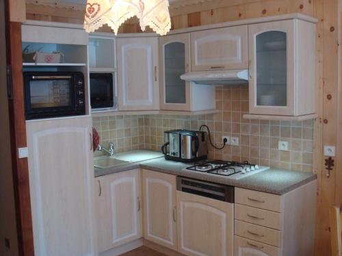 une cuisine avec des armoires blanches et un four à plaques de cuisson dans l'établissement Duplex cosy pour 4 pers avec jardin, exposé sud, centre Valloire, proche télécabine et loisirs - FR-1-263-227, à Valloire