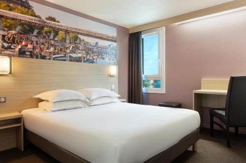 シェルにあるB&B HOTEL Marne-la-Vallée Chellesのベッド、デスク、窓が備わるホテルルームです。