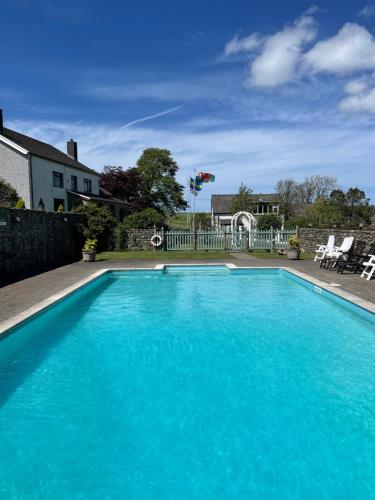 a swimming pool with blue water in front of a house at Trenewydd Farm Holiday Cottages in Cardigan