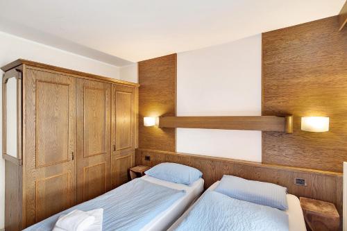 two beds in a room with wood paneling at Casa San Marco n 9 in Livigno
