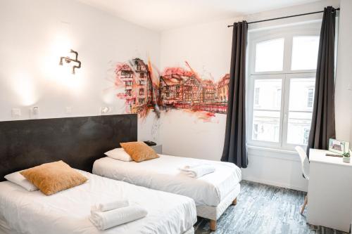 a bedroom with two beds and a window with a painting at Hotel des Arts - Centre Cathédrale in Strasbourg