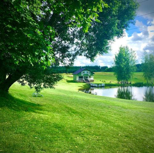 a house in the middle of a field next to a lake at ALANTOS ŽIRGAI Holiday Villas sauna or hottube additional price in Alanta