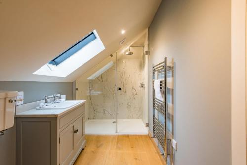 a bathroom with a shower and a sink and a skylight at The Dairy by Bloom Stays in Ulcombe