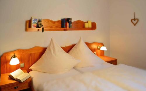 a bedroom with a bed with white sheets and pillows at Ferienwohnungen Haus "Wildschütz" in Frauenau