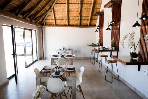 a dining room with tables and chairs and windows at Villa Gracia Guesthouse in Klerksdorp