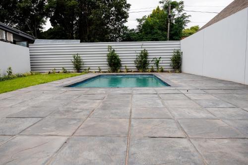 a swimming pool in a backyard with a white fence at Villa Gracia Guesthouse in Klerksdorp