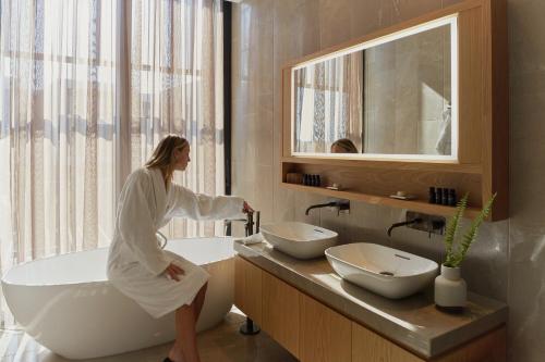 a woman sitting on a bath tub in a bathroom at Minthis Resort in Paphos