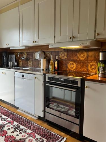 a kitchen with white cabinets and an oven at Villa med fantastisk utsikt in Båstad