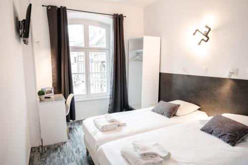 two beds in a small room with a window at Hotel des Arts - Centre Cathédrale in Strasbourg