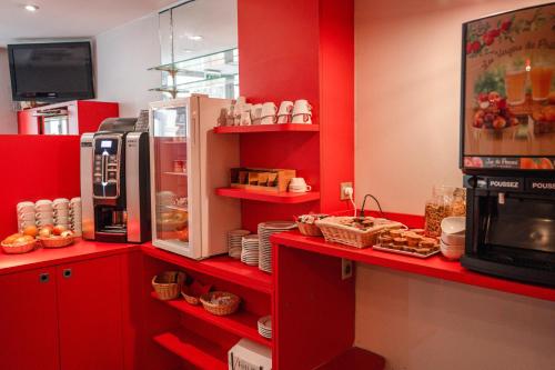 a kitchen with red cabinets and a counter with food at Hotel des Arts - Centre Cathédrale in Strasbourg