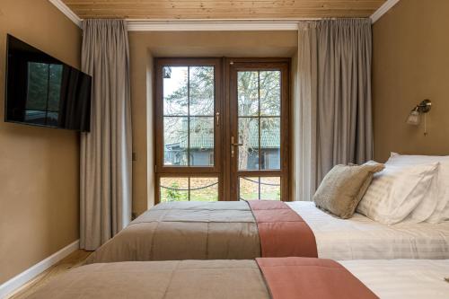 a bedroom with a bed and a large window at Želvė Village & SPA 