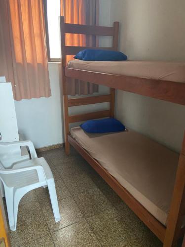 een kamer met 2 stapelbedden en een witte stoel bij Apartamento CF BRAGA in Cabo Frio