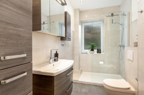 uma casa de banho com um lavatório, um WC e um chuveiro em Modernes Apartment – 2 Boxspringbetten – Zentral em Kassel