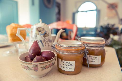two jars of jam and a bowl of apples at La Gare De Millas Chambres d'hôtes in Millas