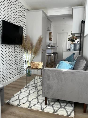 a living room with a couch and a tv on a wall at Somerset House in Northampton