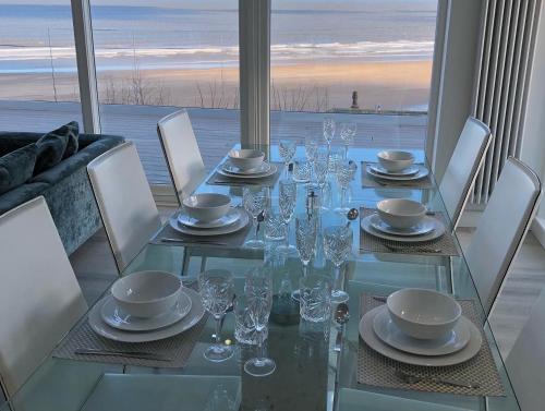 a glass dining table with chairs and a view of the ocean at Filey Beach House in Filey